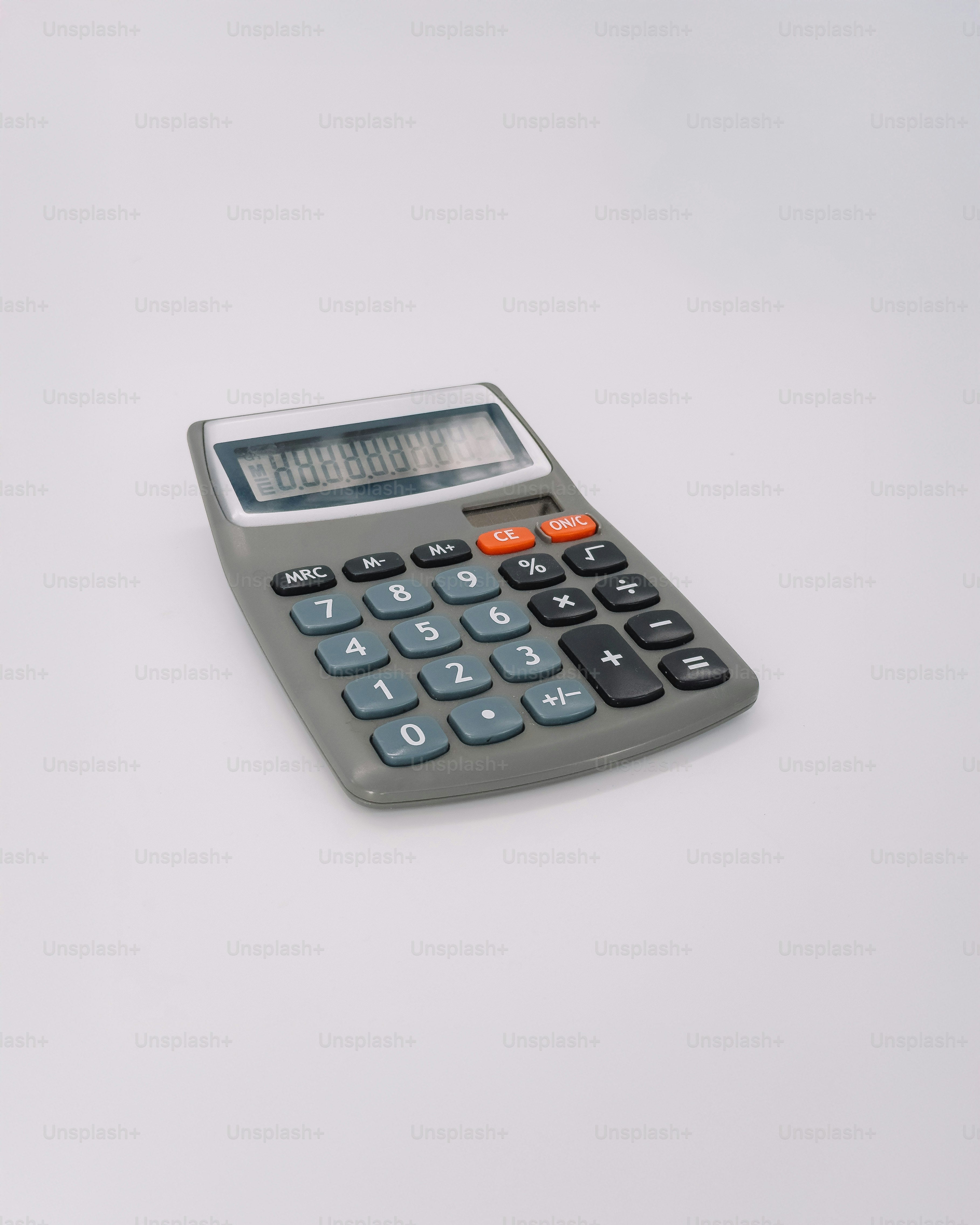 A gray calculator with an lcd screen on white background